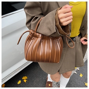 Detail of a brown pleated handbag with fine vertical texture and matching round handle