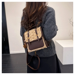 Detail of vintage heart-patterned plush backpack with brown leather trim and pom-pom charm