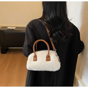 Close-up of white plush pillow bag with brown leather handles and adjustable strap