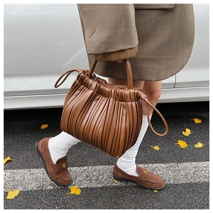 Detail of dark brown pleated handbag featuring soft leather texture and drawstring accents