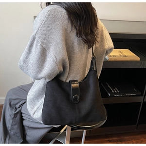 Lifestyle shot of black suede hobo bag with leather strap and metal buckle detail