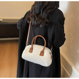Close-up of white plush faux fur texture with brown leather handles on a fashion handbag