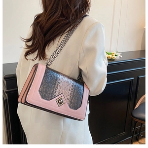Detail of pink and snake skin crossbody bag with gold chain strap worn by a model