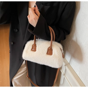 Detail of white faux fur pillow bag with brown leather handles and zipper closure