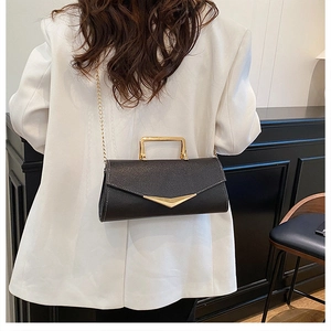 Detailed view of black lychee grain leather crossbody bag with gold V-shaped metal logo