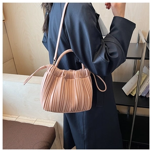Detailed close-up of a pink pleated handbag with rounded handle and fine stitching