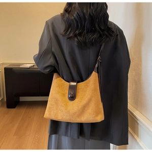 Caramel brown vintage shoulder bag in matte suede leather worn by a model in interior