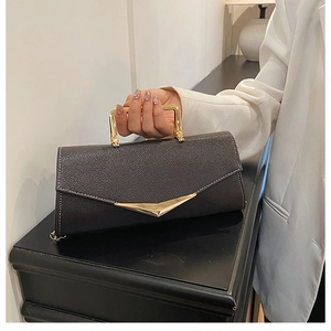Detail of black lychee leather envelope bag with gold metal handle and V-shaped clasp