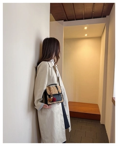 Detail of beige fleece crossbody bag with heart quilting and black leather accents