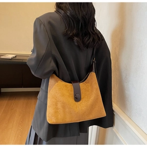 Detail of vintage mustard yellow suede shoulder bag with brown leather strap on model