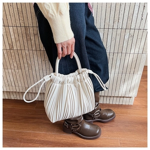 Detail shot of beige pleated handbag featuring soft leather texture and drawstring closure