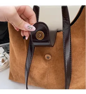 Macro shot of vintage gold magnetic clasp on brown suede tote bag with leather trim