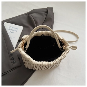 Detail view of cream pleated handbag with magnetic gold clasp and black fabric lining