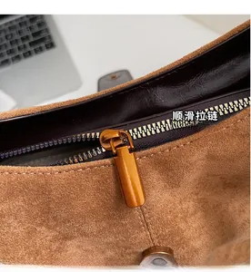 Detail view of the smooth bronze zipper and premium suede fabric on the brown shoulder bag