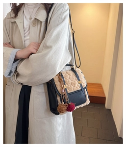 Detail of faux leather backpack featuring beige plush flap with 3D heart pattern and fuzzy charms