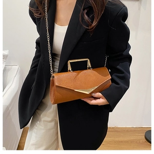 Detail of brown litchi pattern leather bag with gold metal handle and triangle lock