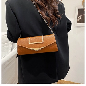 Detail of caramel pebbled leather envelope bag with gold V-metal buckle and chain strap
