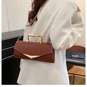 Model wearing a vintage brown PU leather handbag with golden V-clasp and chain strap
