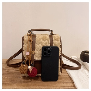 Detailed view of the brown leather and beige faux fur mini backpack with plush charms