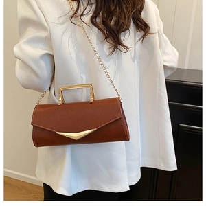 Detailed shot of brown textured leather bag with gold V-shape metal accents and chain strap