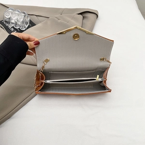 Interior detail of brown envelope bag with herringbone lining and golden magnetic clasp