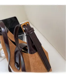 Close-up of adjustable dark chocolate leather strap and golden buckle on brown suede bag