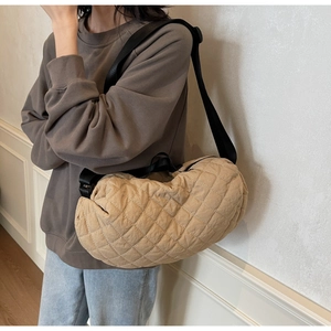 Close-up of khaki quilted puffer crescent bag with diamond stitch and black strap