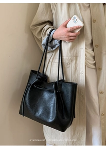 Detail of minimalist black tote bag featuring textured leather and drawstring knots