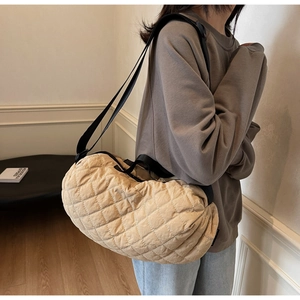 Detail view of large quilted crossbody bag with adjustable black shoulder strap on model