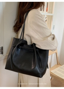 Detail shot of a black oversized tote bag showing textured shiny leather and drawstring