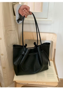 Minimalist black leather tote bag with drawstring detail and slim straps in retro style