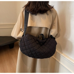 Black quilted nylon crescent bag worn by model in a stylish home setting
