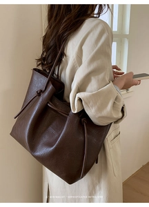 Detail of retro textured brown tote bag featuring minimalist drawstring and side knot design