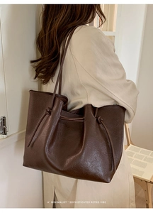 Close-up of minimalist dark brown tote bag showing matte leather texture and drawstring detail