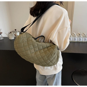 Rear view of olive green quilted hobo bag styled on model in a minimalist cafe