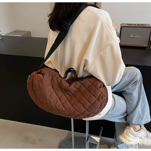 Quilted brown crescent bag on model showing large capacity and adjustable wide strap