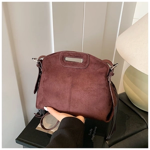 Close-up of vintage reddish-brown suede tote bag with long tassels and cutout handles