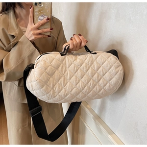 Close-up of beige quilted puffer bag with black adjustable strap on model for size reference