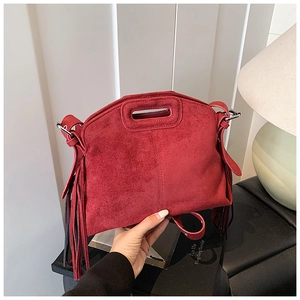 Detail of red suede handbag with fringe decor and hollow handle for a retro style look