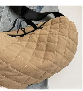 Detailed close-up of quilted khaki canvas shoulder bag with black strap and zipper