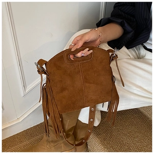 Close-up of brown suede tassel bag featuring bohemian fringe and unique circular handle