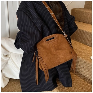 Close-up of brown suede crossbody bag with long tassels and eyelet shoulder strap details