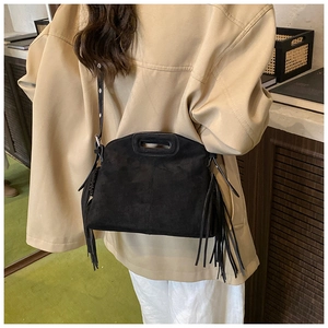 Close-up of black suede crossbody bag with long tassels and integrated top handle