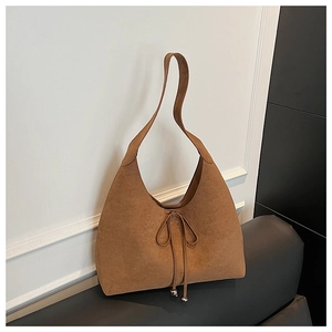 Detail of caramel suede hobo bag featuring bow tie strap and silver metallic bead accents