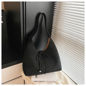 Detail of minimalist black suede shoulder bag with bow tie and silver metallic beads