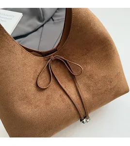 Detail of dark brown suede tote featuring a ribbon bow and decorative silver beads