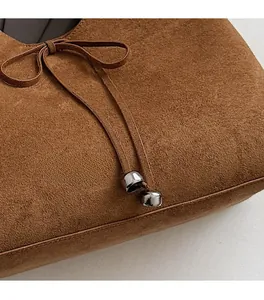 Close-up of brown suede tote bag with delicate bow knot and silver metallic hardware detailing