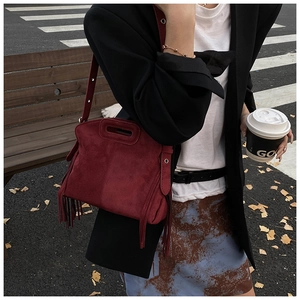 Detail of burgundy suede tote with stylish fringe accents and adjustable shoulder strap