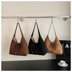 Three suede hobo bags in dark brown, black, and khaki with elegant bow detailing