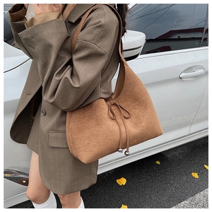 Close-up of brown suede hobo bag featuring delicate tie-up detail and silver beads
